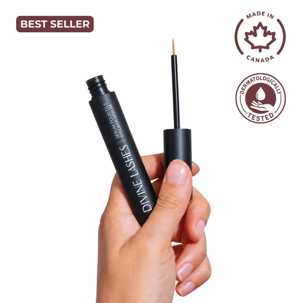 A feminine hand holding the open Divine Lashes serum bottle with the applicator tip ready for use against a clean white background.
