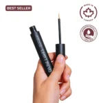 A feminine hand holding the open Divine Lashes serum bottle with the applicator tip ready for use against a clean white background.